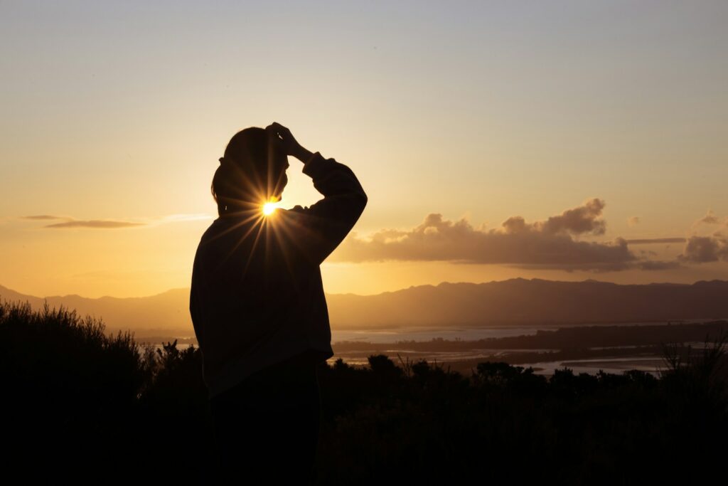 A man standing on top of a hill looking at the sun